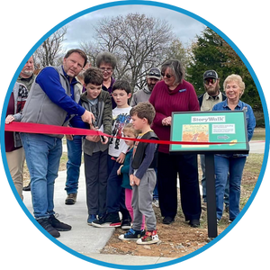 They partnered with the City of Gravette Parks Department and the Gravette Police Department to install a StoryWalk at a local park. The photo is of the ribbon cutting.